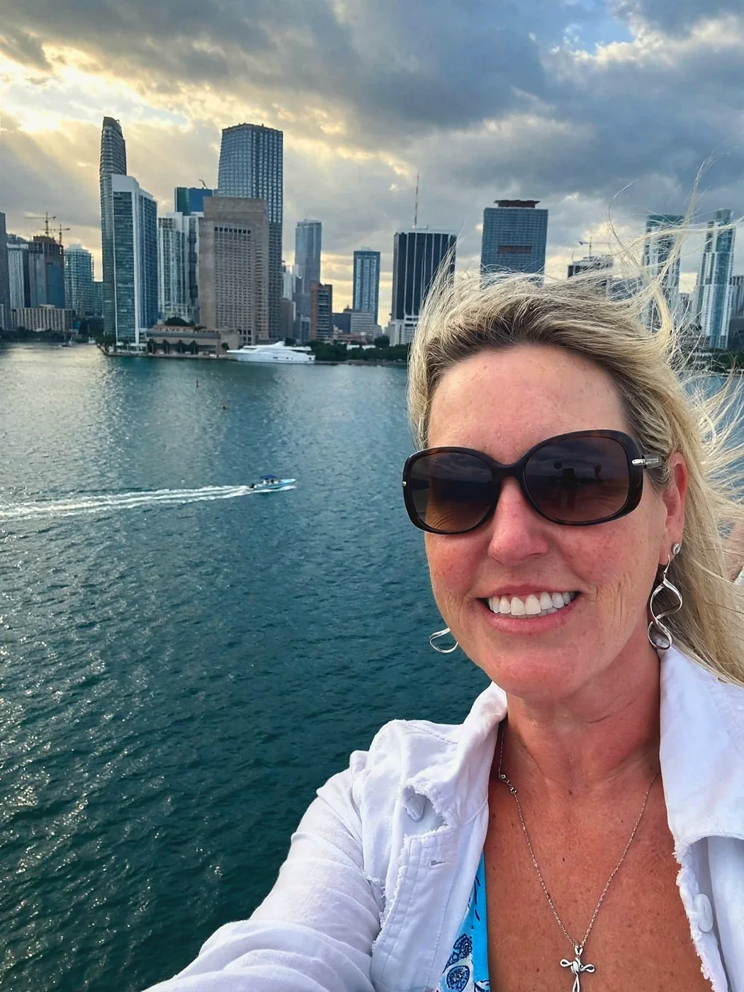 Jennifer Gregg on a ship deck at sunset with the Miami skyline behind her